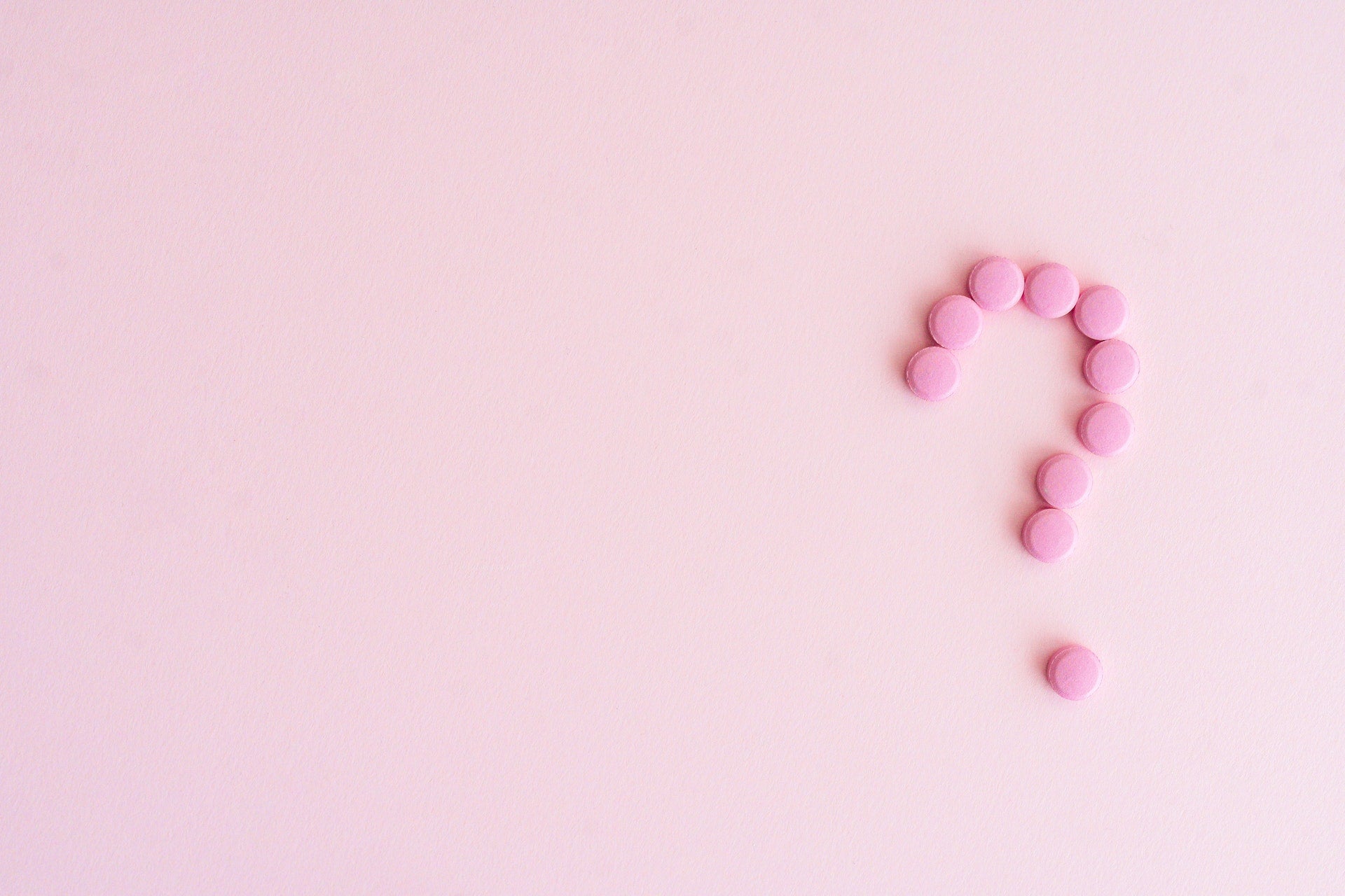 Question mark symbol spelled with pink color tablets laid out in pink background cute stationery designs